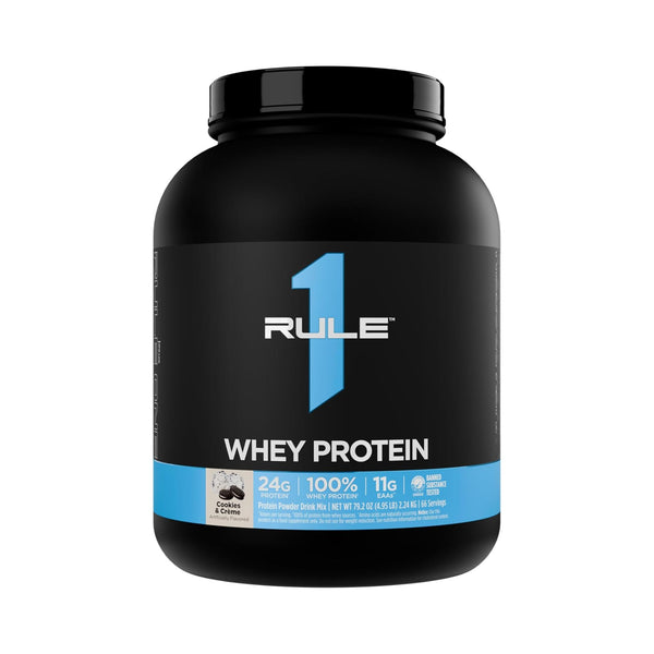 A black tub of Rule 1 Whey Protein powder with a blue and white label, shown on a plain white background.